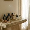 Curated collection of niche French perfume bottles displayed on an antique stone pedestal in an atelier.