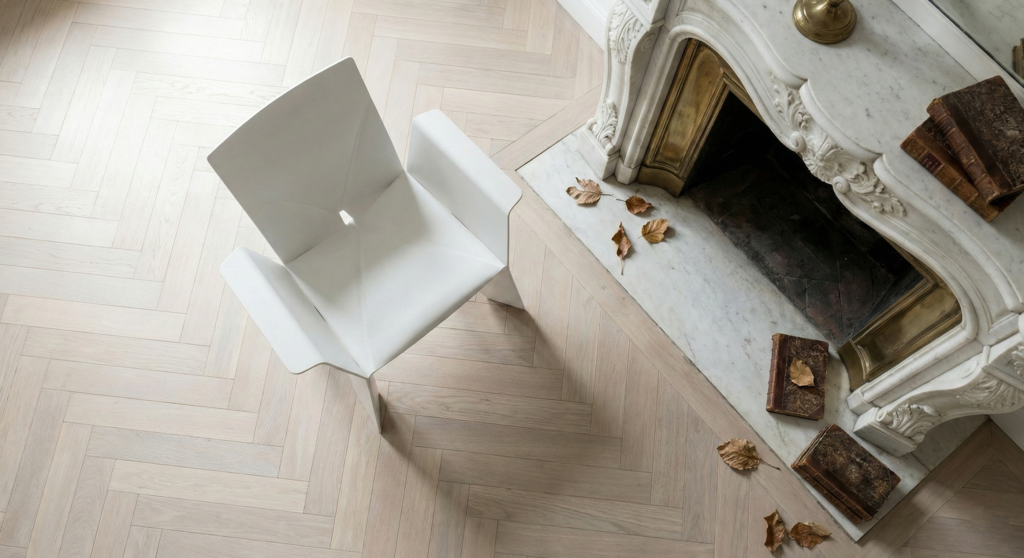 Modern white geometric chair next to a classic marble fireplace with antique books, showcasing a curated French furniture mix.
