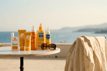 Selection of French pharmacy sunscreens including La Roche-Posay, Bioderma, and Avène on a table overlooking the Mediterranean sea