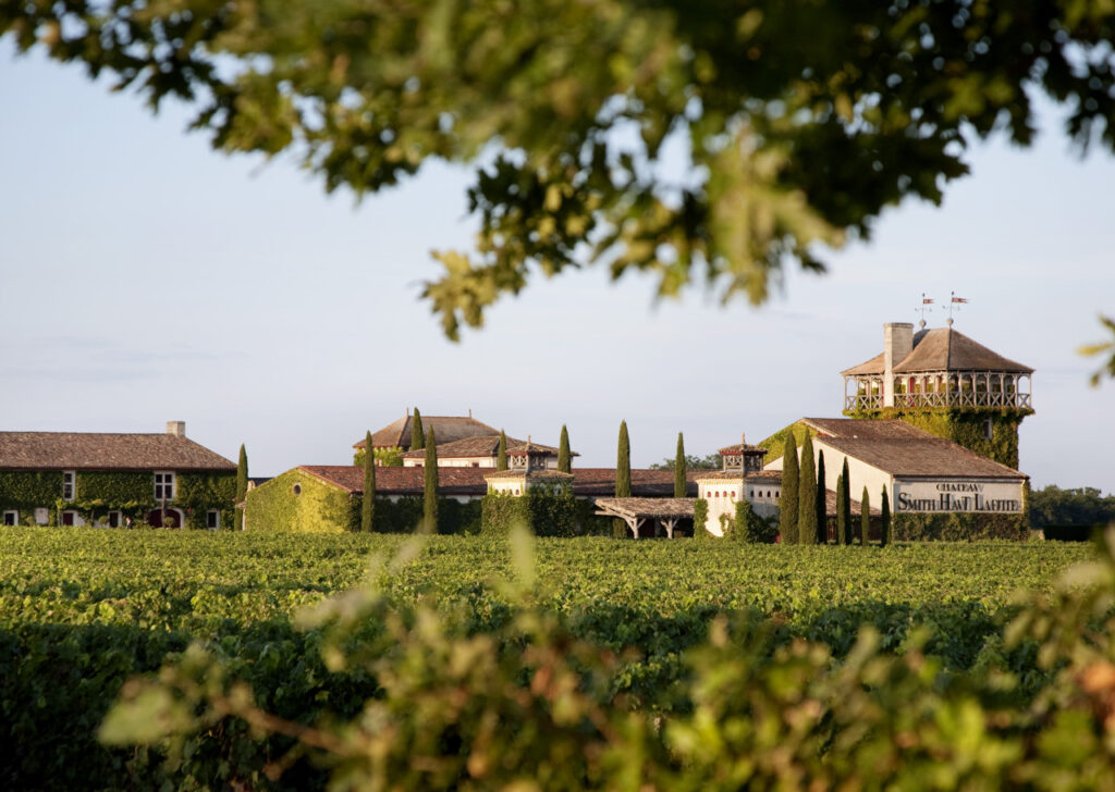 Panoramic view of the Chateau Smith Haut Lafitte estate featuring its historic stone buildings and lush vineyards.