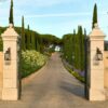 Entrance pillars of Airelles Château de la Messardière leading to a scenic cypress-lined driveway in Saint-Tropez