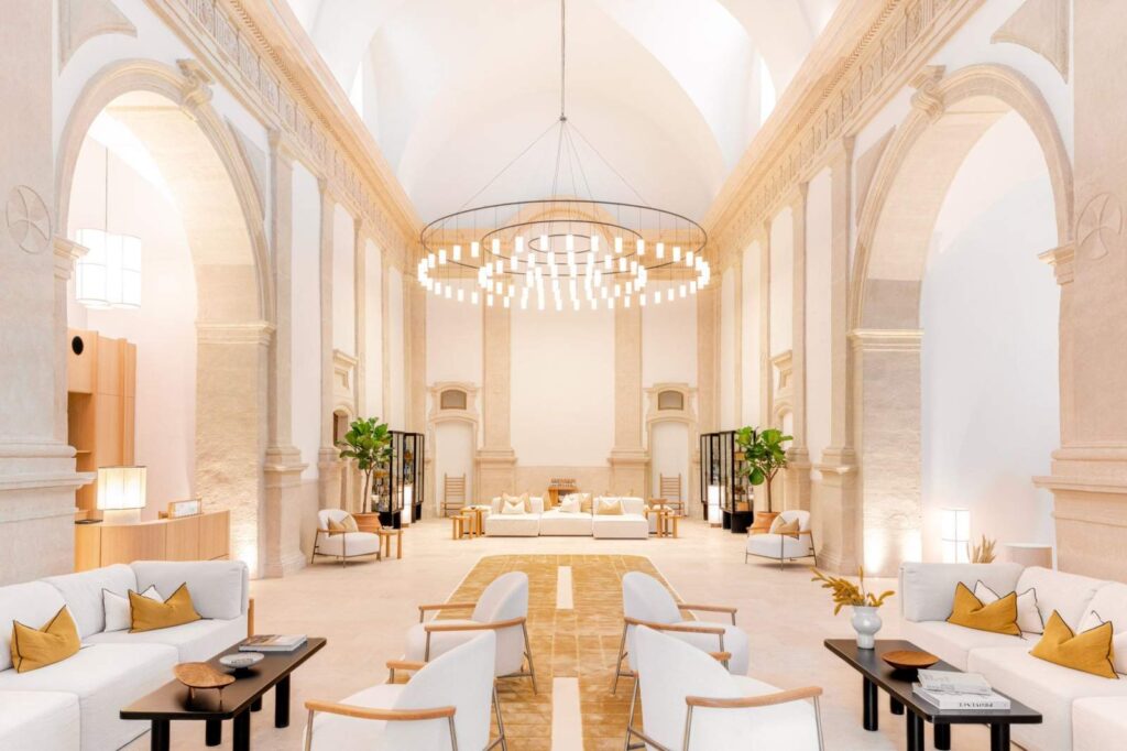 Lounge area of Couvent des Minimes featuring high vaulted ceilings, arched pillars, and modern white furniture