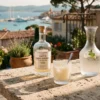 A luxury bottle of artisanal pastis and a ribbed crystal glass with cloudy yellow liquid on a sun-drenched stone terrace in Saint-Tropez