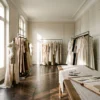 Golden sunlight streaming into a historical Parisian fashion archive filled with curated vintage couture on racks