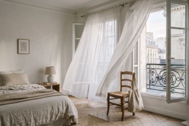 A serene bedroom in Paris with a linen tote bag, evoking a quiet luxury travel mood.