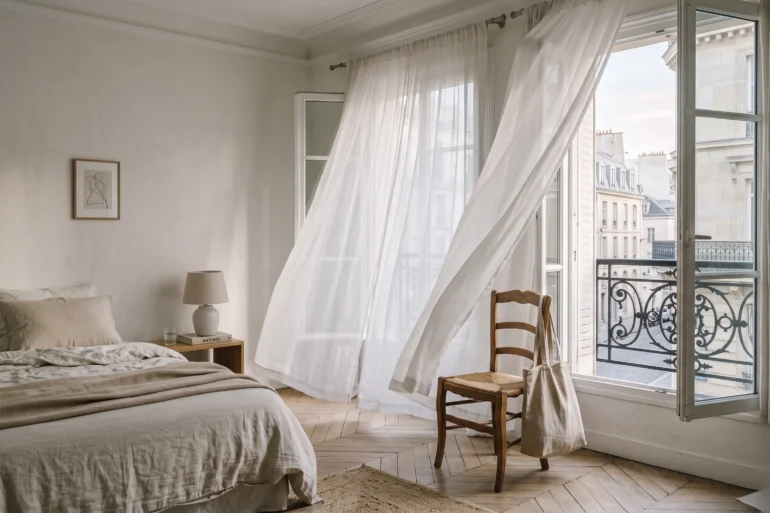 A serene bedroom in Paris with a linen tote bag, evoking a quiet luxury travel mood.