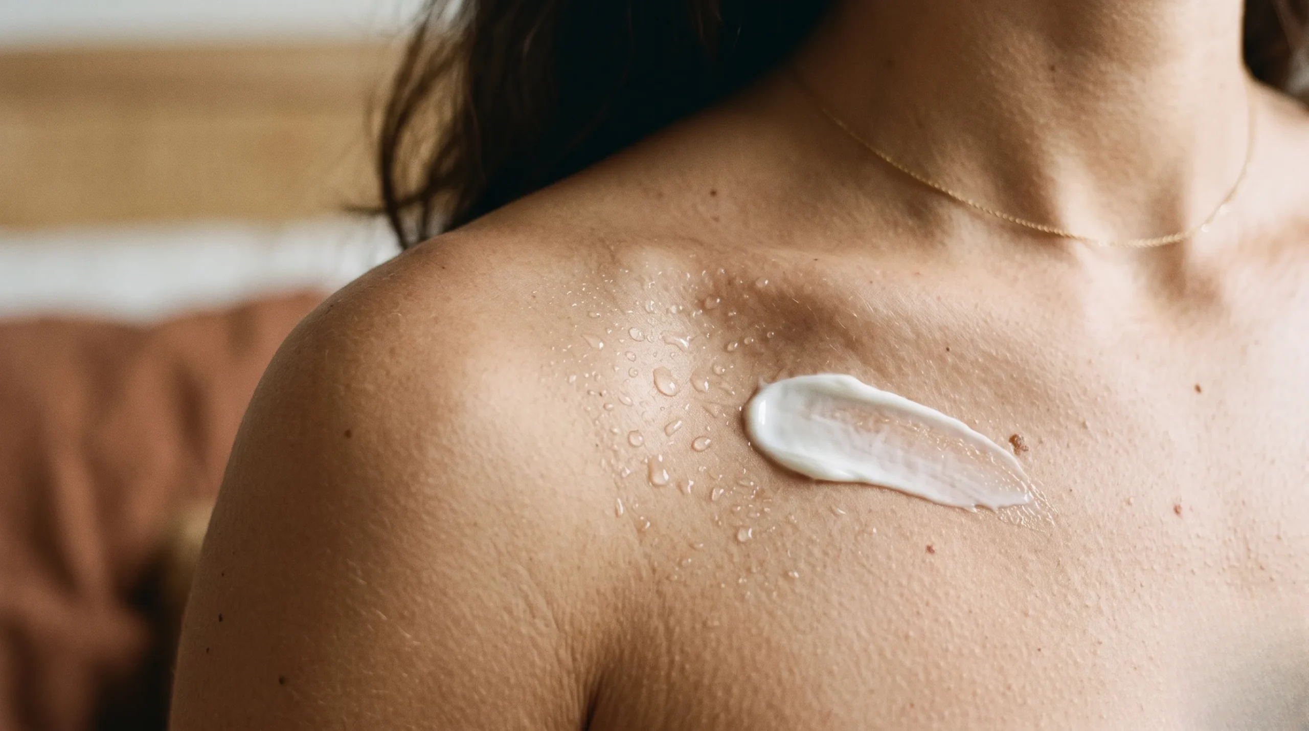 A close-up details of clean skincare textures and golden facial oil on a textured travertine stone surface